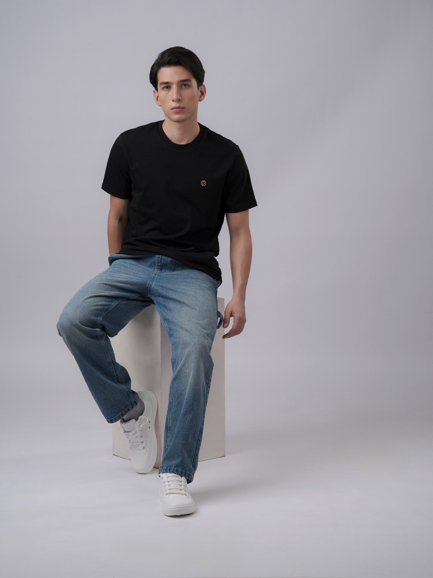 Person wearing a black regular fit t-shirt with simple logo - front view3