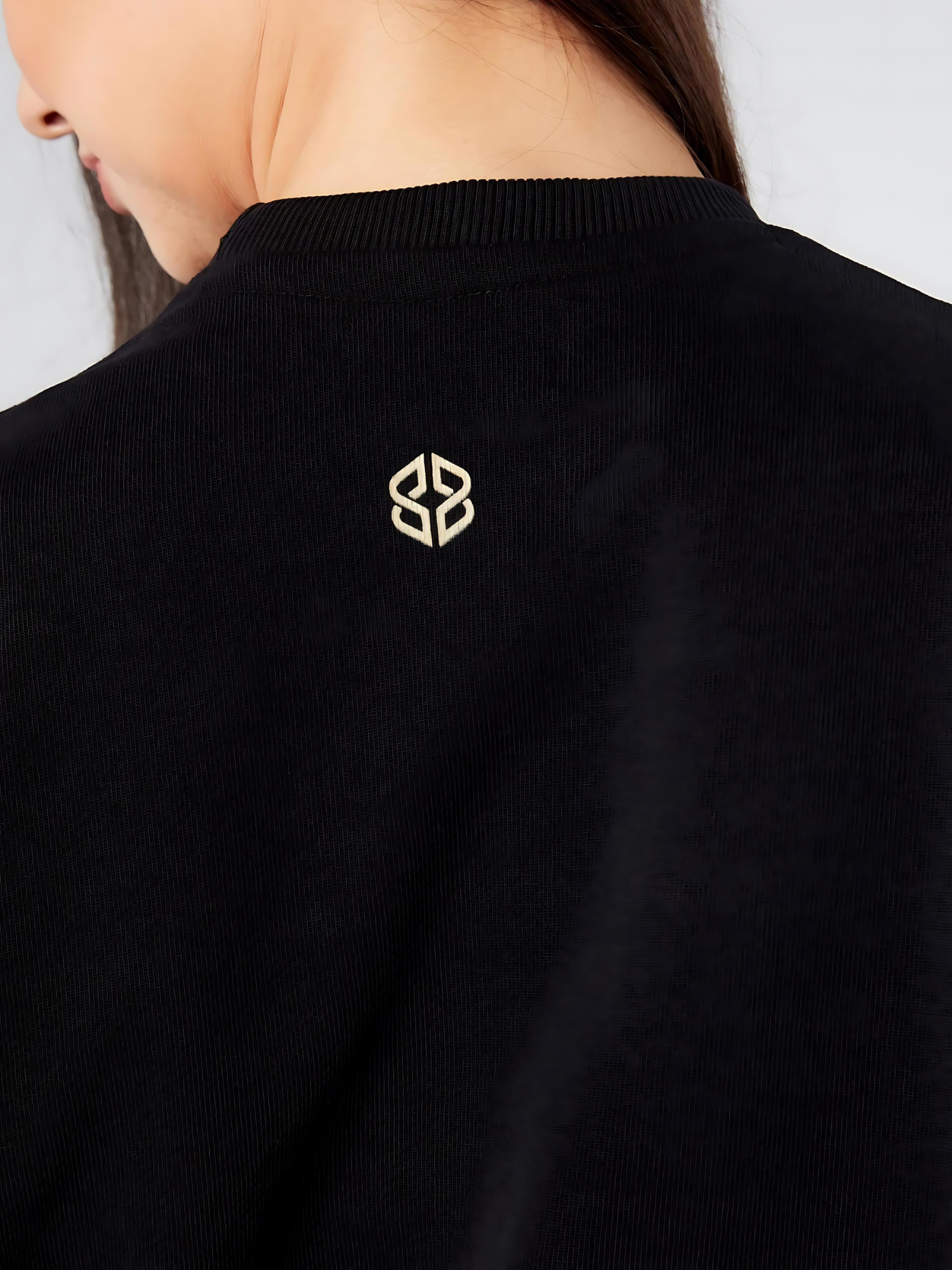 Close-up view of women's relaxed fit cotton rich soft black sweatshirt with back neck golden logo - Lexanber UK